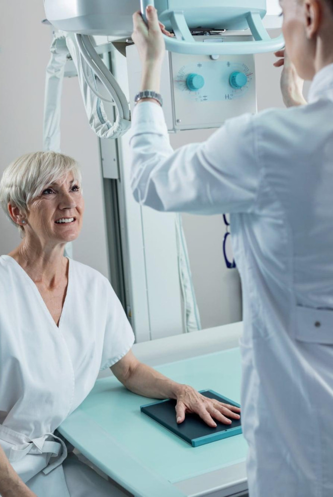 Happy mature woman medical technician hand xray procedure clinic 1