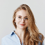 Headshot of blonde woman wearing glasses in smart attire.